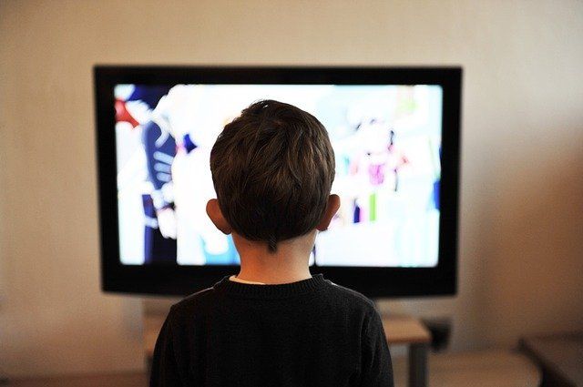 Un petit garçon devant un écran de télévision.