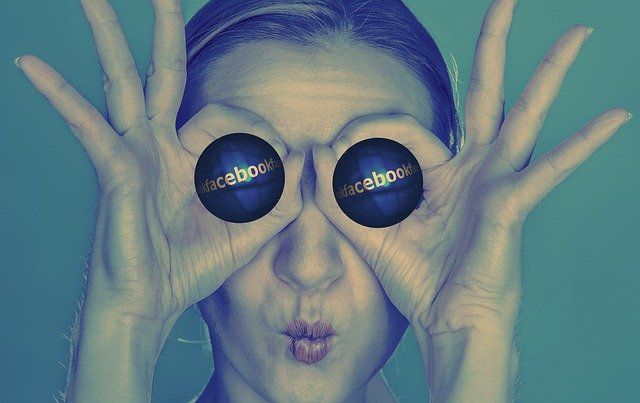 Une femme tient deux boules sur ses yeux, sur lesquelles il est écrit Facebook.