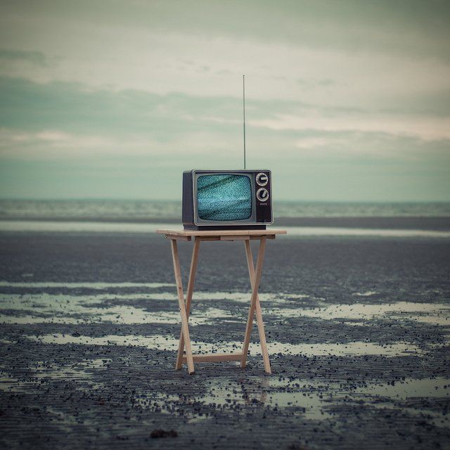 Télévision ancienne posée sur un support en bois.