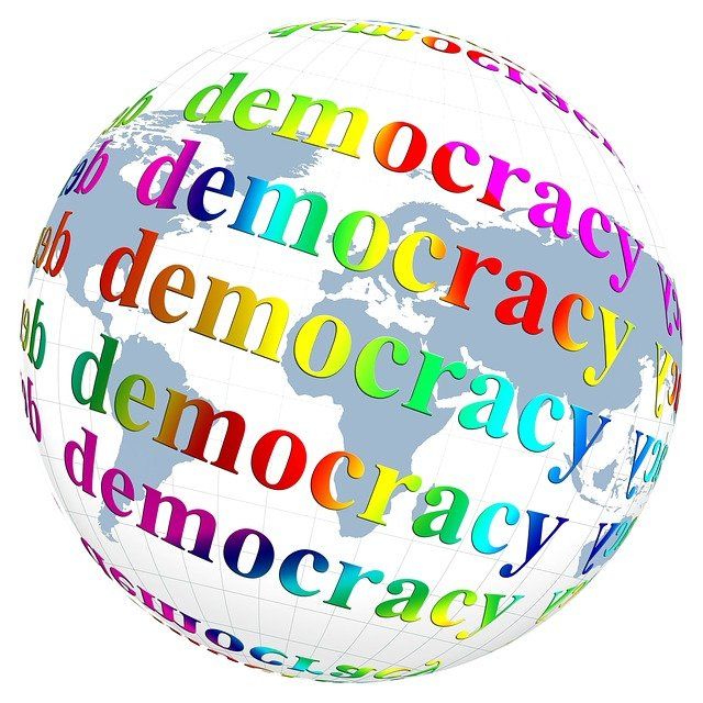 Globe terrestre sur lequel est écrit démocratie en anglais.