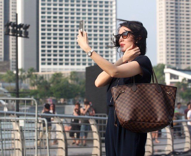 Une femme portant des lunettes de soleil réalise un selfie.