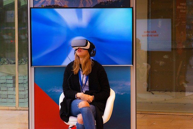 Femme assise avec un casque de réalité virtuelle sur les yeux.